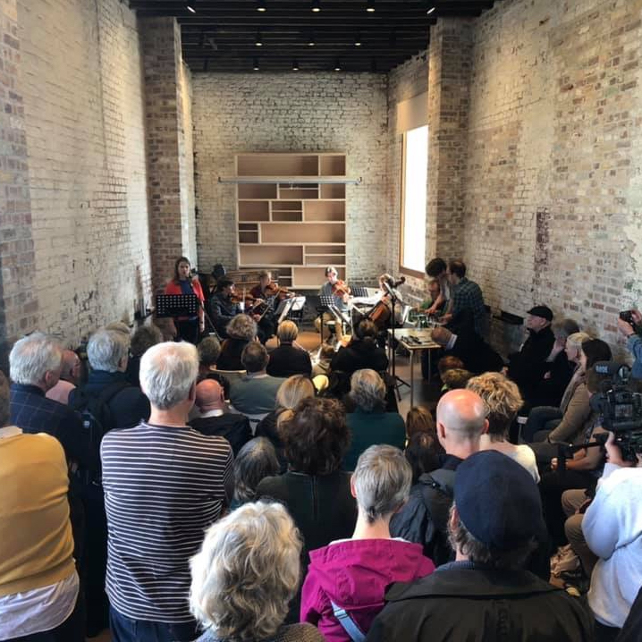 An audience is gathered to hear music being played by a string quartet in the historic surroundings of Customs House, Folkestone.